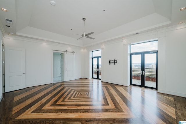 spare room with dark parquet flooring, a barn door, a raised ceiling, and french doors