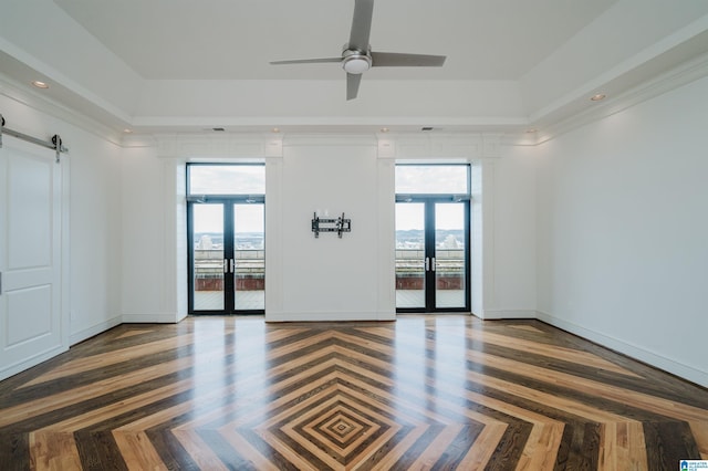 spare room with french doors, dark parquet floors, a wealth of natural light, and a barn door