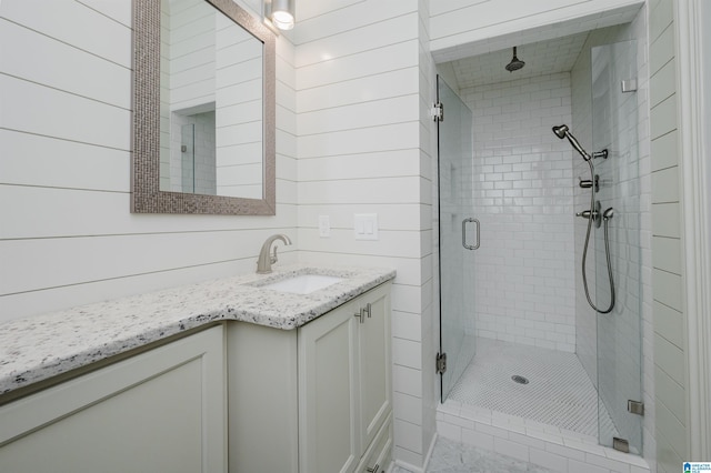 bathroom with wooden walls, vanity, and walk in shower