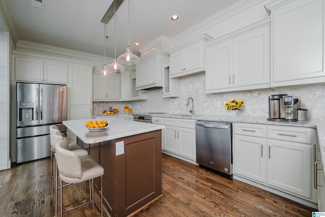 kitchen with appliances with stainless steel finishes, a kitchen island, white cabinetry, and hanging light fixtures