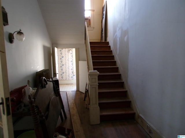 staircase with wood-type flooring and lofted ceiling