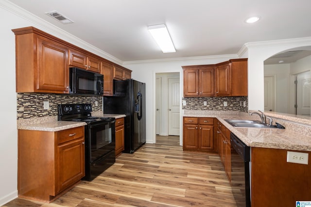 kitchen featuring light wood-type flooring, ornamental molding, sink, and black appliances