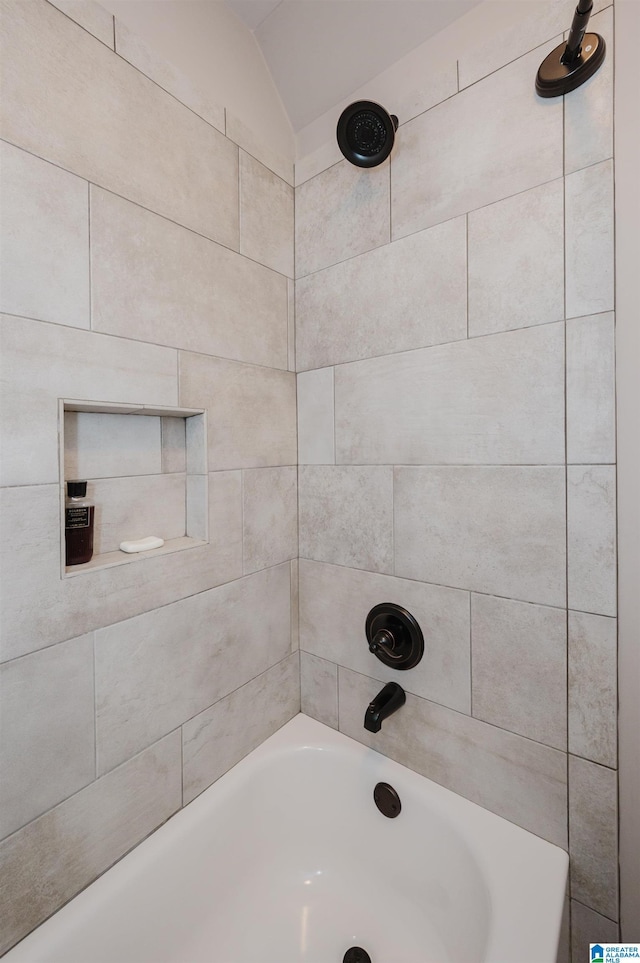 bathroom featuring tiled shower / bath combo and vaulted ceiling