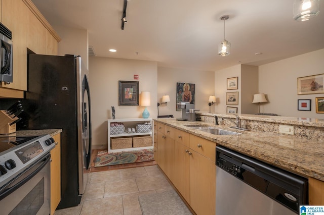 kitchen with light stone counters, light brown cabinets, stainless steel appliances, a sink, and hanging light fixtures