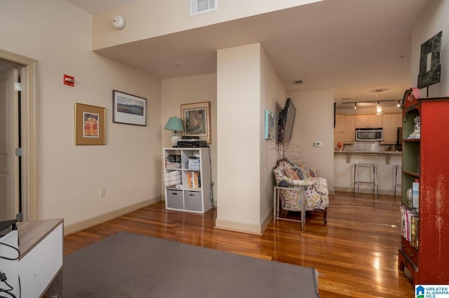 living area featuring dark wood-type flooring, visible vents, and baseboards