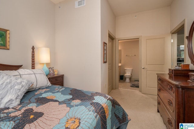 bedroom with light carpet, ensuite bath, and visible vents