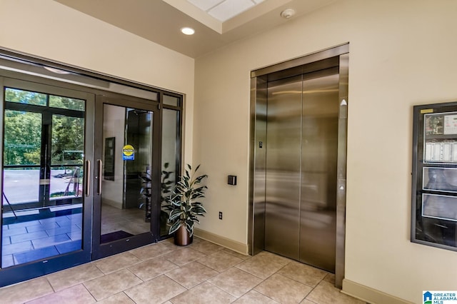 entryway featuring light tile patterned flooring, recessed lighting, baseboards, french doors, and elevator