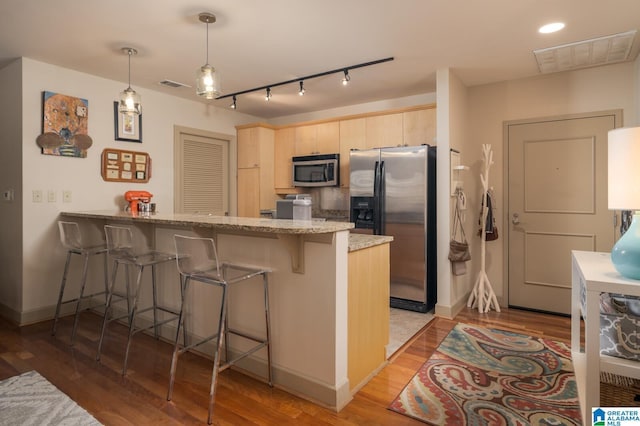 kitchen with visible vents, appliances with stainless steel finishes, a peninsula, hanging light fixtures, and light brown cabinets