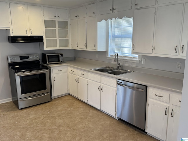 kitchen featuring appliances with stainless steel finishes, sink, light tile patterned floors, and white cabinets