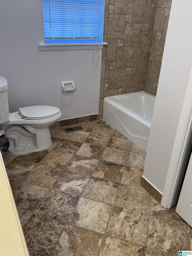 bathroom featuring tiled shower / bath and toilet