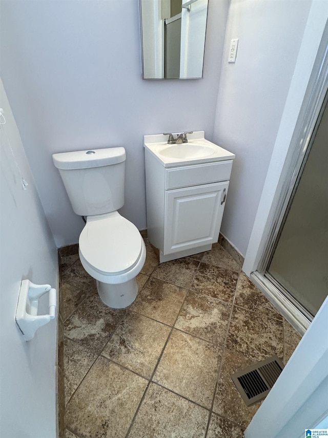 bathroom with vanity, a shower with door, and toilet