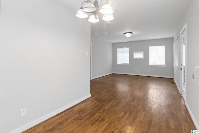 empty room with dark hardwood / wood-style floors and a chandelier