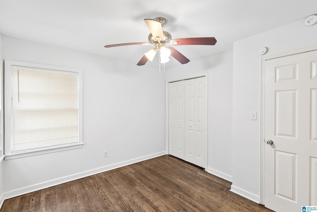 unfurnished bedroom featuring ceiling fan, dark wood-style flooring, a closet, and baseboards