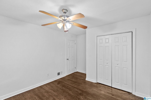 unfurnished bedroom featuring a ceiling fan, visible vents, baseboards, a closet, and dark wood-style floors