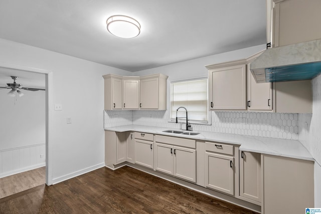 kitchen featuring tasteful backsplash, ceiling fan, light stone counters, dark wood-type flooring, and a sink