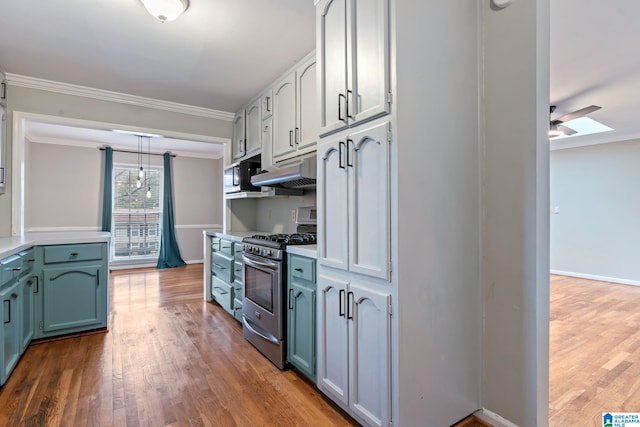 kitchen featuring gas range, ornamental molding, light countertops, under cabinet range hood, and pendant lighting