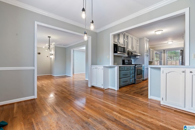 kitchen with under cabinet range hood, stainless steel appliances, white cabinets, light countertops, and decorative light fixtures