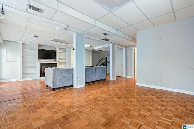 interior space featuring built in shelves, visible vents, a fireplace, and baseboards