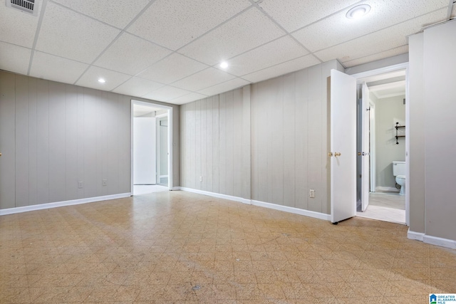 spare room featuring recessed lighting, baseboards, a drop ceiling, and light floors