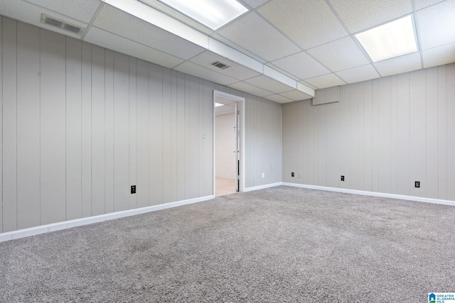 finished below grade area with baseboards, visible vents, a drop ceiling, and carpet flooring