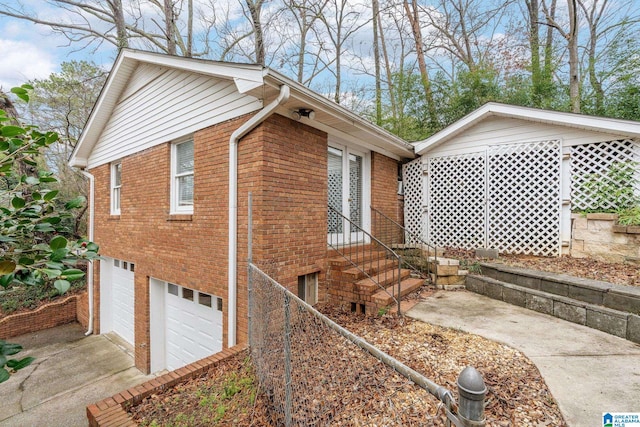 view of side of home with a garage, concrete driveway, brick siding, and fence