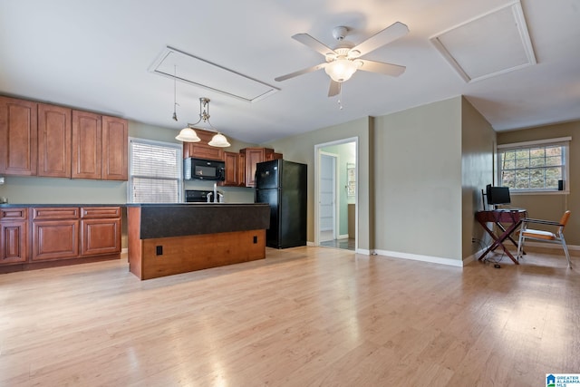 kitchen featuring brown cabinetry, a center island, decorative light fixtures, light wood-type flooring, and black appliances