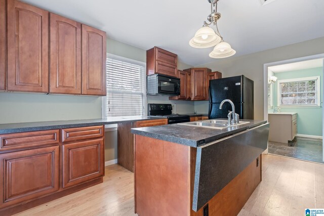 kitchen with dark countertops, hanging light fixtures, a sink, an island with sink, and black appliances