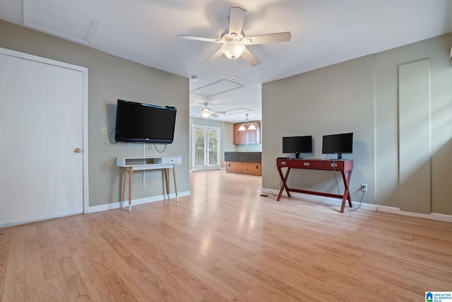 living room with ceiling fan, light wood-type flooring, attic access, and baseboards