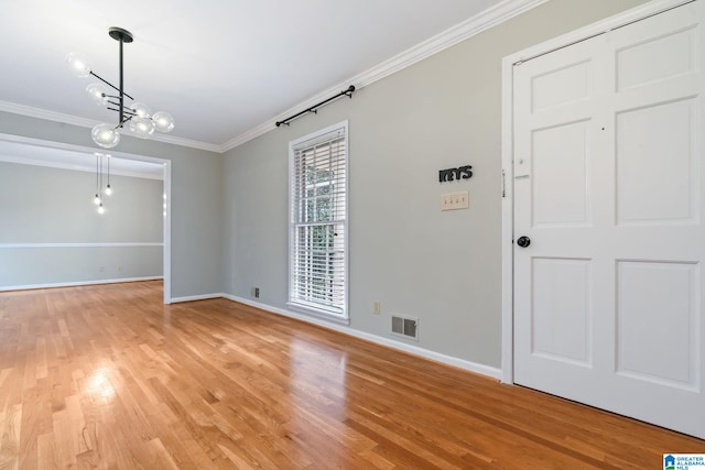 unfurnished room featuring crown molding, a notable chandelier, visible vents, light wood-type flooring, and baseboards