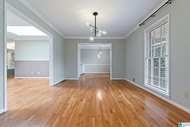 unfurnished dining area featuring light wood-style floors, a notable chandelier, baseboards, and crown molding