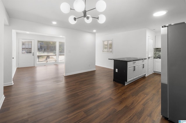 kitchen with dark hardwood / wood-style floors, stainless steel fridge, white cabinets, backsplash, and a barn door