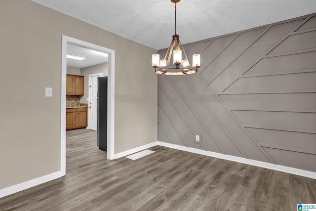 unfurnished dining area with wood-type flooring and a chandelier