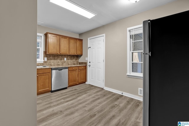 kitchen with stainless steel appliances, light wood-type flooring, and decorative backsplash