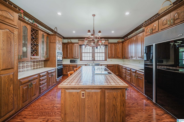 kitchen featuring dark hardwood / wood-style flooring, a kitchen island, an inviting chandelier, and black appliances