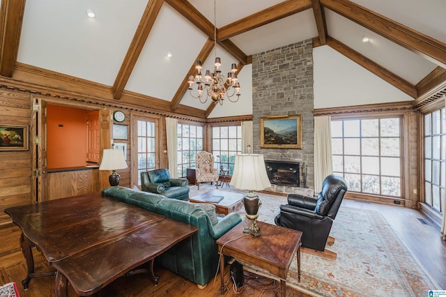 living room with hardwood / wood-style floors, high vaulted ceiling, a fireplace, beamed ceiling, and an inviting chandelier