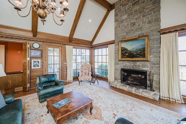 living room featuring a stone fireplace, a chandelier, high vaulted ceiling, beamed ceiling, and hardwood / wood-style floors