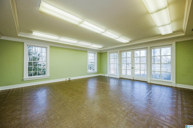 empty room with a raised ceiling, ornamental molding, and dark parquet flooring