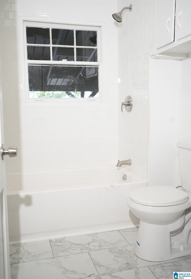 bathroom featuring tiled shower / bath combo and toilet