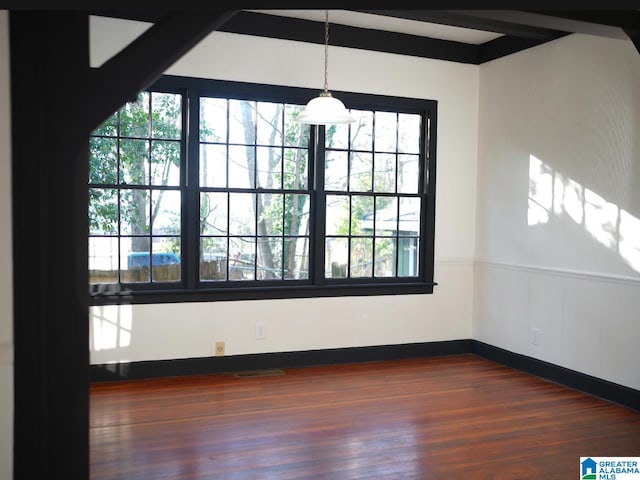 spare room featuring beamed ceiling and dark hardwood / wood-style flooring