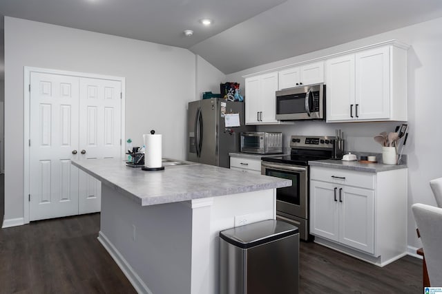 kitchen with vaulted ceiling, appliances with stainless steel finishes, dark hardwood / wood-style floors, white cabinets, and a center island