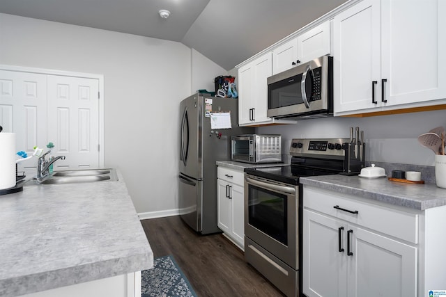 kitchen with appliances with stainless steel finishes, lofted ceiling, sink, white cabinets, and dark hardwood / wood-style flooring