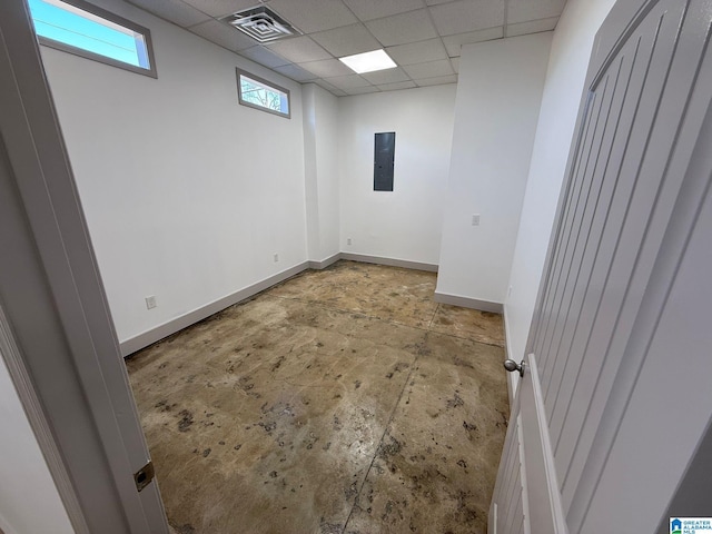 unfurnished room with concrete flooring, electric panel, and a drop ceiling