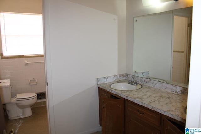 bathroom featuring vanity, toilet, and tile walls