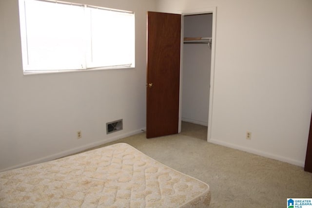 unfurnished bedroom featuring light colored carpet and a closet