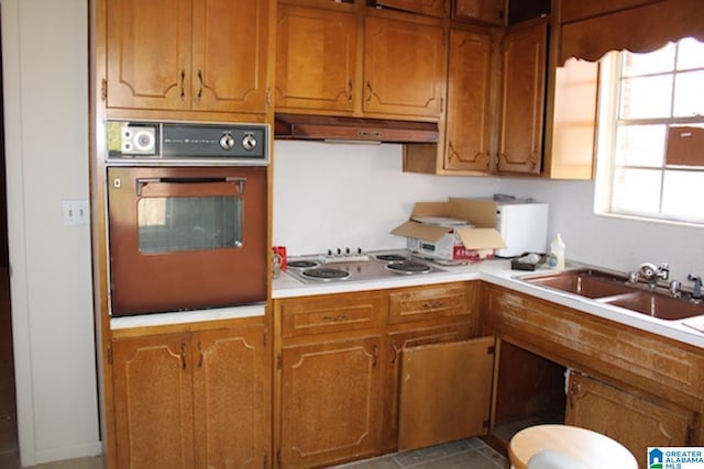 kitchen with wall oven, extractor fan, cooktop, and sink