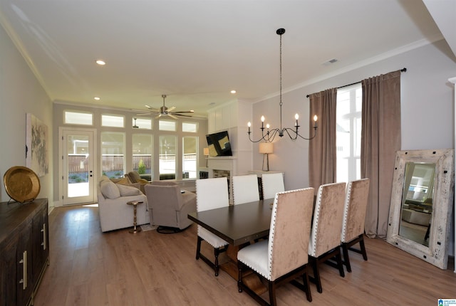 dining space featuring light wood-type flooring, ornamental molding, and a fireplace