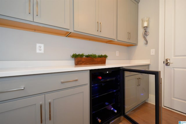 bar with beverage cooler and light wood-style flooring