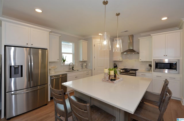 kitchen featuring white cabinetry, wall chimney exhaust hood, appliances with stainless steel finishes, and a center island