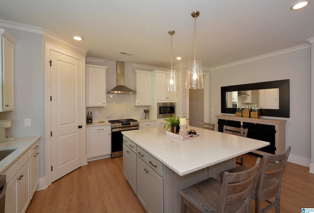 kitchen featuring stainless steel appliances, light countertops, white cabinetry, a kitchen island, and wall chimney exhaust hood