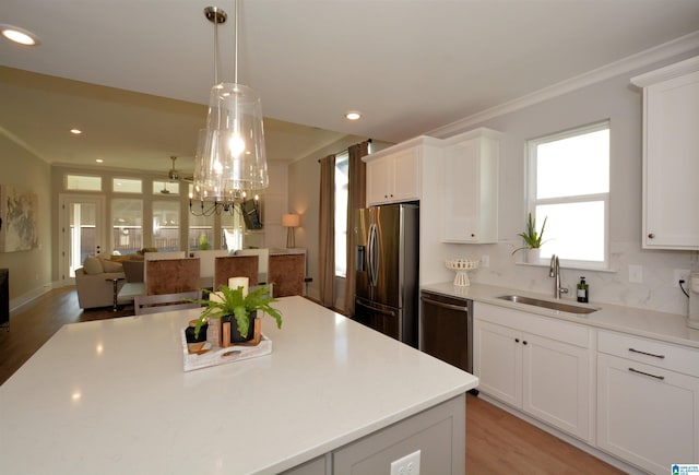 kitchen with a sink, white cabinets, light countertops, dishwasher, and stainless steel fridge